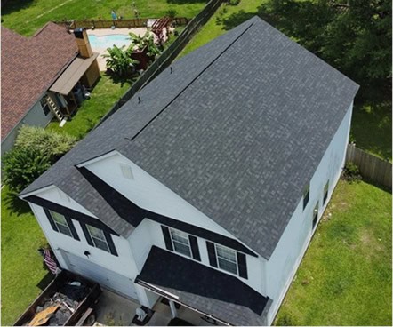 Aerial view of a two-story white house with a dark gray shingled roof, surrounded by grass and a fenced backyard with a pool visible in the neighboring property.