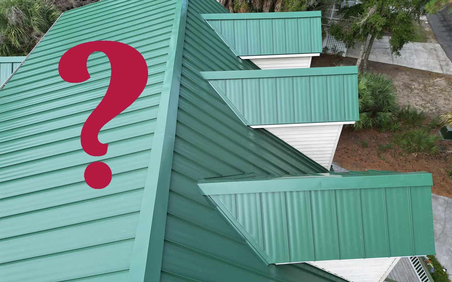 A green metal roof with multiple dormers, seen from above, with a large red question mark digitally added to the image.